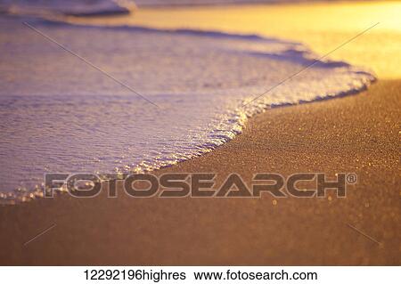 Stock Photograph - Wave Washing on Sand at Sunset, Shallow Depth of Field. Fotosearch