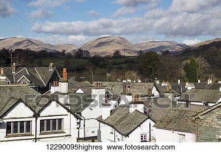 Stock Photograph - White houses and rooftops with mountains in the distance; Hawkshead, England. Fotosearch