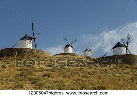 Stock Photograph - Windmills in a row against a blue sky; Consuegra, Spain. Fotosearch