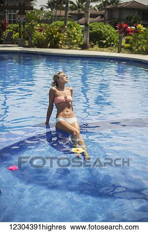 Stock Photograph - Woman at a resort enjoying the pool; Island of Hawaii, Hawaii, United States of America. Fotosearch