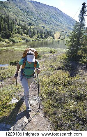 Stock Photograph - Woman backpacker hikes along Upper Fuller Lake in the Kenai National Wildlife Refuge on the Kenai Peninsula in South-central Alaska. Fotosearch