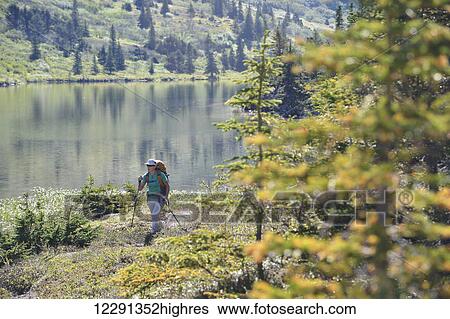 Stock Photograph - Woman backpacker hikes along Upper Fuller Lake in the Kenai National Wildlife Refuge on the Kenai Peninsula in South-central Alaska. Fotosearch