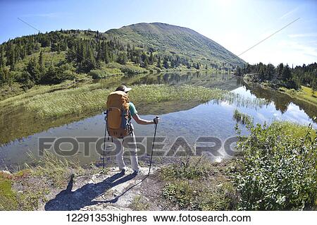 Stock Photograph - Woman backpacker hikes along Upper Fuller Lake in the Kenai National Wildlife Refuge on the Kenai Peninsula in South-central Alaska. Fotosearch