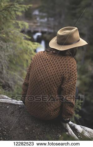 Woman in hat perched on ledge overlooking river in Girdwood, Southcentral Alaska. View Large Photo Image Stock Image - Woman in hat perched on ledge overlooking river in Girdwood, Southcentral Alaska.. Fotosearch