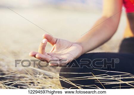 Stock Photograph - Woman meditating practicing yoga outdoors. Fotosearch
