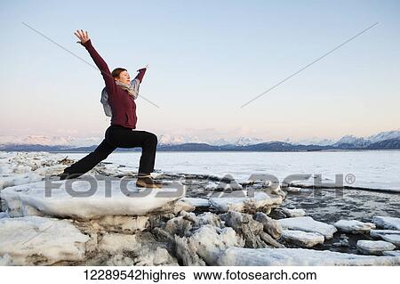 Stock Photograph - Woman practices yoga on an ice chunk on a beach in Homer, Southcentral Alaska. Fotosearch