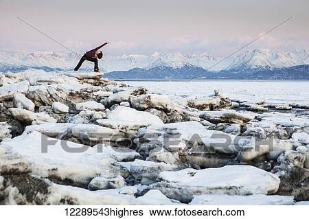 Stock Photograph - Woman practices yoga on an ice chunk on a beach in Homer, Southcentral Alaska. Fotosearch