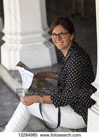 Stock Photography - Woman sitting on a step looking at a map; Bangkok, Thailand. Fotosearch