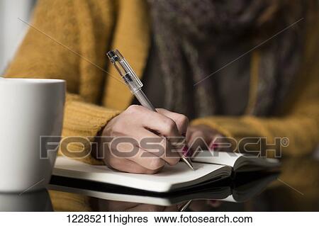 Stock Photograph - Woman writing thoughts in a journal; Toronto, Ontario, Canada. Fotosearch