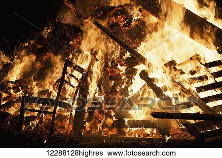 Stock Photograph - Wooden chair and pallets burning in bonfire, Guy Fawkes Night; London, England. Fotosearch