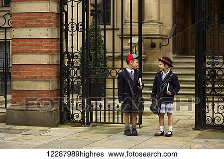 Young boy and girl students in uniform talking outside the school; London, England View Large Photo Image Stock Photograph - Young boy and girl students in uniform talking outside the school; London, England. Fotosearch
