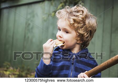 Stock Photograph - Young boy eating a s'more outdoors and getting sticky; St. Albert, Alberta, Canada. Fotosearch