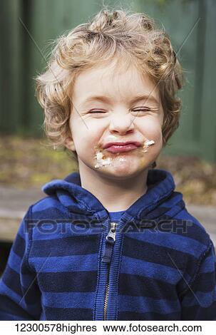 Stock Photograph - Young boy eating a s'more outdoors and getting sticky; St. Albert, Alberta, Canada. Fotosearch