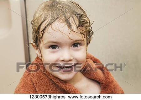 Stock Photograph - Young boy smiling and getting dry with a towel after having a shower in a bathroom; St. Albert, Alberta, Canada. Fotosearch