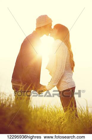Young Couple in Love, Kissing at Sunset View Large Photo Image Stock Photograph - Young Couple in Love, Kissing at Sunset. Fotosearch
