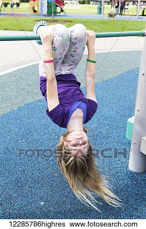 Young girl hanging upside down at the playground; Salmon Arm, British Columbia, Canada View Large Photo Image Stock Photograph - Young girl hanging upside down at the playground; Salmon Arm, British Columbia, Canada. Fotosearch