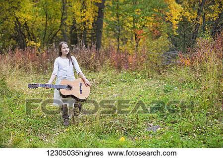 Young girl holding a guitar outdoors in the Hatcher Pass area, Southcentral Alaska, autumn View Large Photo Image Stock Photograph - Young girl holding a guitar outdoors in the Hatcher Pass area, Southcentral Alaska, autumn. Fotosearch