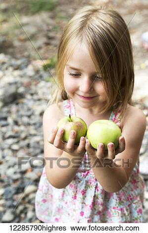 Stock Photograph - Young girl holding fresh green apples; Salmon Arm, British Columbia Canada. Fotosearch
