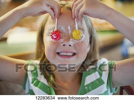 Young girl holding suckers over her eyes: Richmond, British Columbia, Canada View Large Photo Image Picture - Young girl holding suckers over her eyes: Richmond, British Columbia, Canada. Fotosearch
