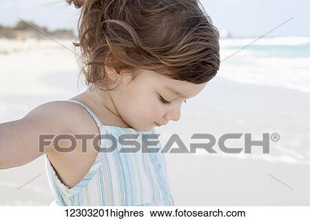 Stock Photograph - Young girl on a white sand beach at the water's edge; Varadero, Cuba. Fotosearch