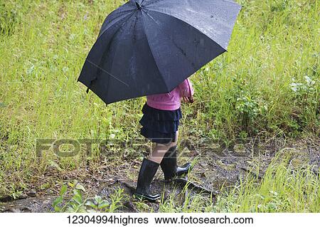 Young girl walking on a muddy trail with rubber boots and an umbrella on a rainy day, Palmer, Southcentral Alaska, summer View Large Photo Image Stock Photograph - Young girl walking on a muddy trail with rubber boots and an umbrella on a rainy day, Palmer, Southcentral Alaska, summer. Fotosearch