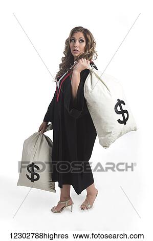 Stock Photograph - Young graduating woman holding money bags to symbolize the costs of her education; Edmonton, Alberta, Canada. Fotosearch