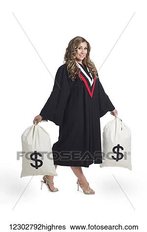 Stock Photograph - Young graduating woman holding money bags to symbolize the costs of her education; Edmonton, Alberta, Canada. Fotosearch