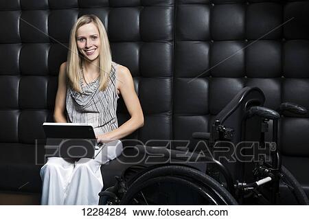 Picture - Young professional business woman who is a paraplegic working on her computer; St. Albert, Alberta, Canada. Fotosearch