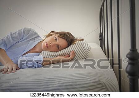 Young woman lying on her bed View Large Photo Image Stock Photograph - Young woman lying on her bed. Fotosearch
