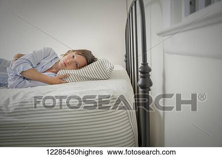 Young woman lying on her bed View Large Photo Image Stock Photograph - Young woman lying on her bed. Fotosearch