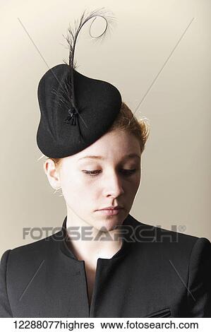Stock Photograph - Young woman with red hair in a black hat with feathers; Caldecott, England. Fotosearch