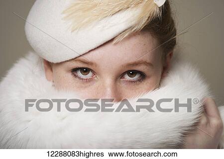 Young woman with red hair in white feathered hat with fur hiding mouth; Caldecott, England View Large Photo Image Stock Photograph - Young woman with red hair in white feathered hat with fur hiding mouth; Caldecott, England. Fotosearch