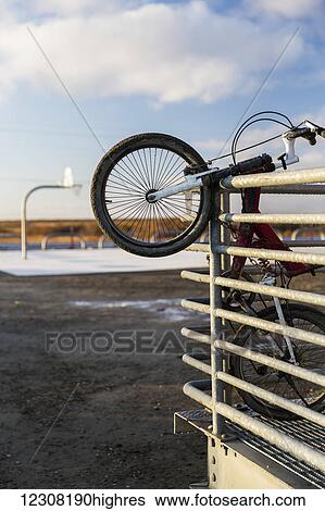 Stock Photograph - A bicycle hangs on the railing of the Alakanuk Public School porch, Alakanuk, Yukon Delta, Arctic Alaska, USA, Fall. Fotosearch
