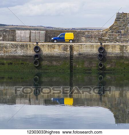 A blue and yellow truck parked along the water's edge and reflected in the harbour; Macduff, Aberdeenshire, Scotland View Large Photo Image Stock Photograph - A blue and yellow truck parked along the water's edge and reflected in the harbour; Macduff, Aberdeenshire, Scotland. Fotosearch