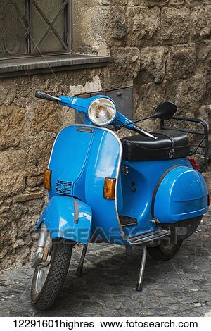 Stock Photograph - A blue motorized scooter parked outside a building; Orvieto, Umbria, Italy. Fotosearch