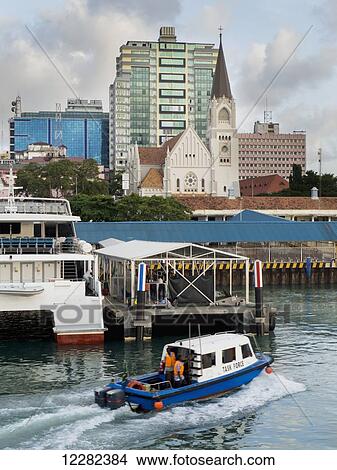 Picture - A boat in the harbour and a view of St. Joseph's Cathedral; Dar es Salaam, Tanzania. Fotosearch