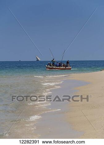 Stock Image - A boat with fisherman off Zanzibar beach; Zanzibar, Tanzania. Fotosearch