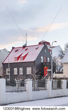 Stock Photograph - A brown building with red roof at dusk in winter; Reykjavik, Iceland. Fotosearch