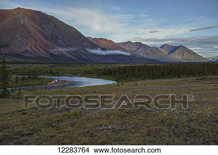 A campsite occupied by canoes and tents along the Wind River in the Peel Watershed; Yukon, Canada View Large Photo Image Picture - A campsite occupied by canoes and tents along the Wind River in the Peel Watershed; Yukon, Canada. Fotosearch