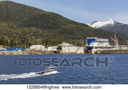 A charter fishing boat passes in front of the waterfront docks and shipyards, Ketchikan, Southeast Alaska, Spring View Large Photo Image Stock Photograph - A charter fishing boat passes in front of the waterfront docks and shipyards, Ketchikan, Southeast Alaska, Spring. Fotosearch