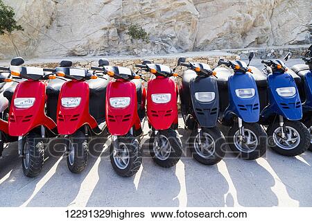 A colourful row of scooters lined up at a rental agency next to the cruise ship port for tourists to rent; Island of Mykonos, Greek Islands, Greece View Large Photo Image Stock Photograph - A colourful row of scooters lined up at a rental agency next to the cruise ship port for tourists to rent; Island of Mykonos, Greek Islands, Greece. Fotosearch