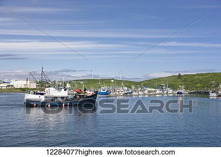 Stock Photograph - A commercial fishing boat motors towards Sand Point Harbor, Southwestern Alaska, USA, Summer. Fotosearch