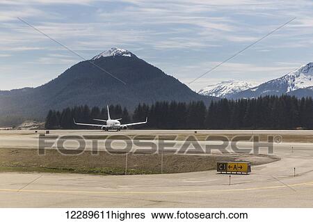 A commercial passenger airplane lands at the Juneau airport with snow capped peaks in the background, Juneau, Southeast Alaska, USA, Spring View Large Photo Image Stock Photograph - A commercial passenger airplane lands at the Juneau airport with snow capped peaks in the background, Juneau, Southeast Alaska, USA, Spring. Fotosearch