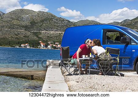 A couple shares a kiss outside their camper van at a beach along the coast; Slano, Croatia View Large Photo Image Stock Photograph - A couple shares a kiss outside their camper van at a beach along the coast; Slano, Croatia. Fotosearch