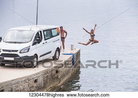 Stock Photograph - A couple stops for an early morning swim and shower after camping in their van; Croatia. Fotosearch
