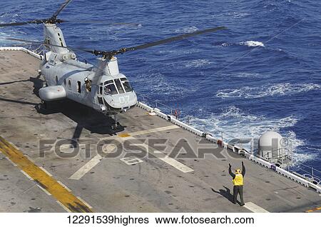 A crewman onboard the USS Peleliu (LHA-5) guides a CH-46 Sea Knight helicopter in for a landing; Hawaii, United States of America View Large Photo Image Stock Photograph - A crewman onboard the USS Peleliu (LHA-5) guides a CH-46 Sea Knight helicopter in for a landing; Hawaii, United States of America. Fotosearch