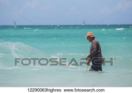 A Cuban male fisherman casts a net in the Caribbean sea to catch fish in the blue water on a sunny day; Varadero, Cuba View Large Photo Image Stock Photograph - A Cuban male fisherman casts a net in the Caribbean sea to catch fish in the blue water on a sunny day; Varadero, Cuba. Fotosearch