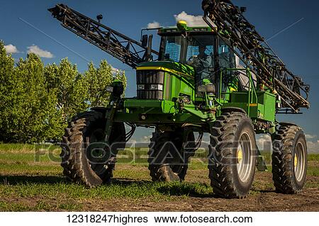 Stock Photograph - A farmer drives a sprayer across a farm field; Herschel, Saskatchewan, Canada. Fotosearch