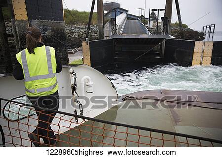 Stock Photograph - A ferry worker waits to help dock the bow of ferry at Gravina Island Ferry Port, Gravina Island, Ketchikan, Southeast Alaska, USA, Spring. Fotosearch