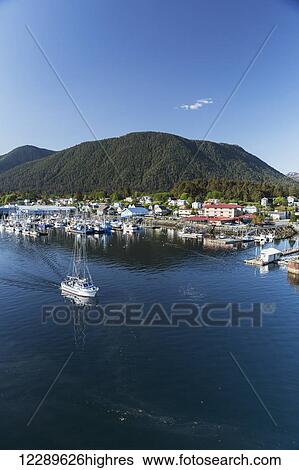 Stock Photograph - A fishing boat motors out of Sitka Harbor on a clear day, Southeast Alaska, USA, Summer. Fotosearch